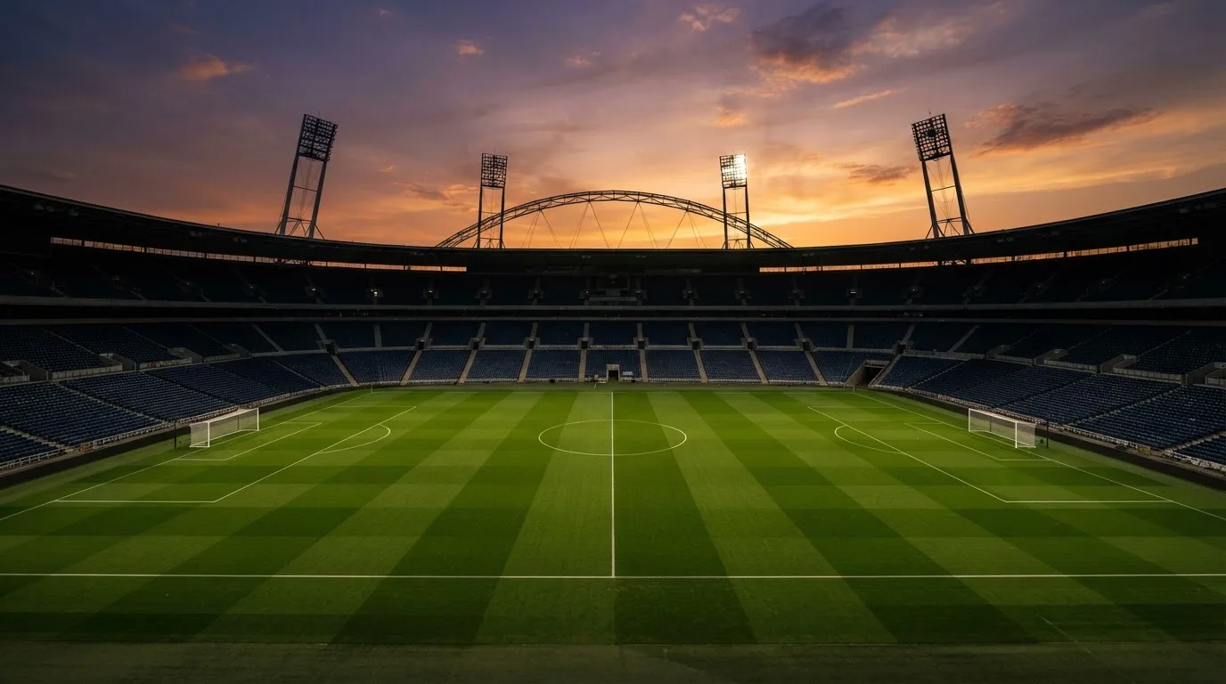Un estadio de fútbol vacío con torres de iluminación al atardecer