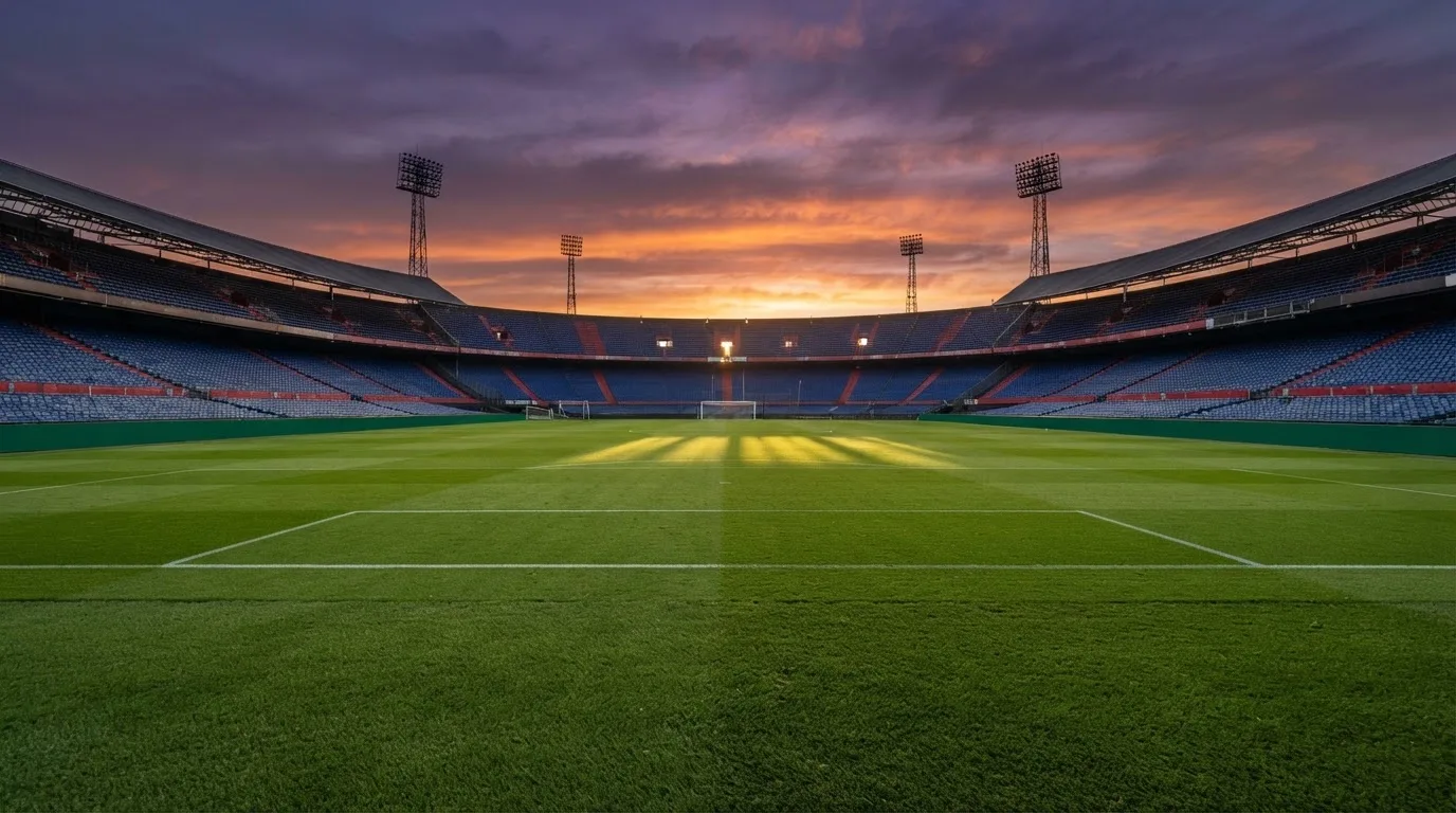 Un estadio de fútbol vacío con torres de iluminación al atardecer