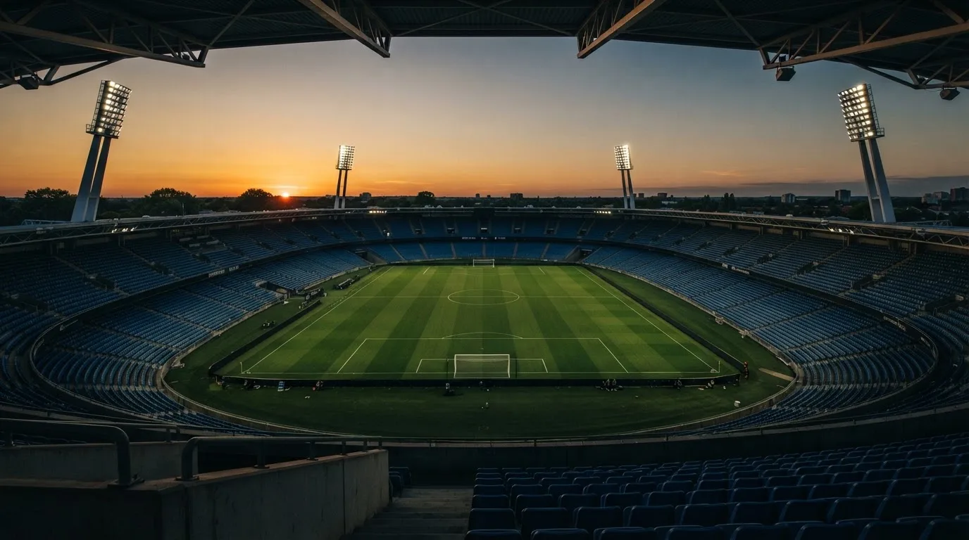 Un estadio de fútbol vacío con torres de iluminación al atardecer