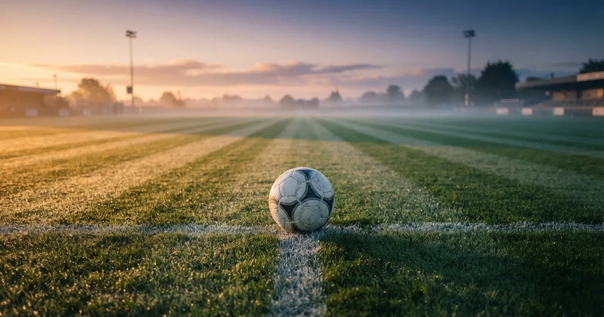 Un balón en el punto central de un campo de césped a la luz de la mañana