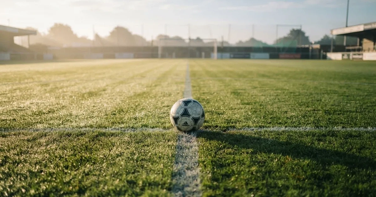 Un balón en el punto central de un campo de césped a la luz de la mañana