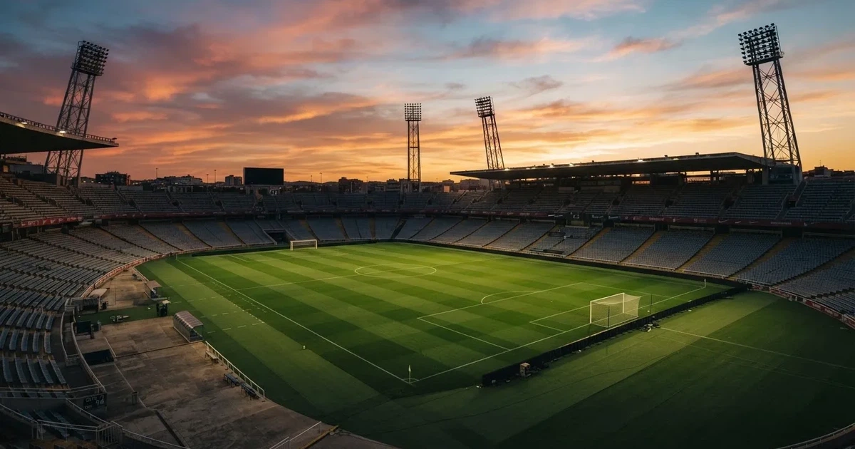 Un estadio de fútbol vacío con torres de iluminación al atardecer
