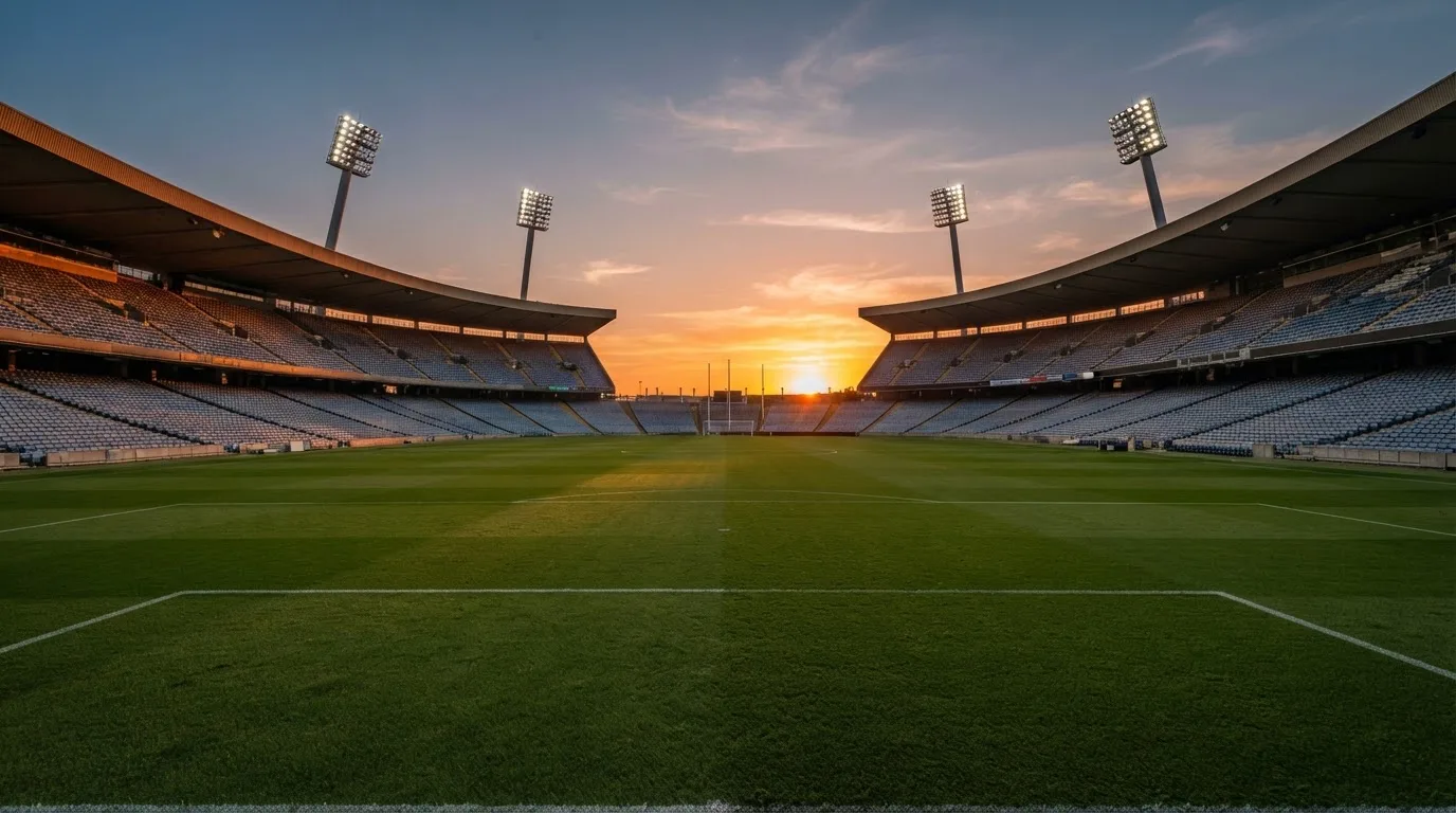 Un estadio de fútbol vacío con torres de iluminación al atardecer