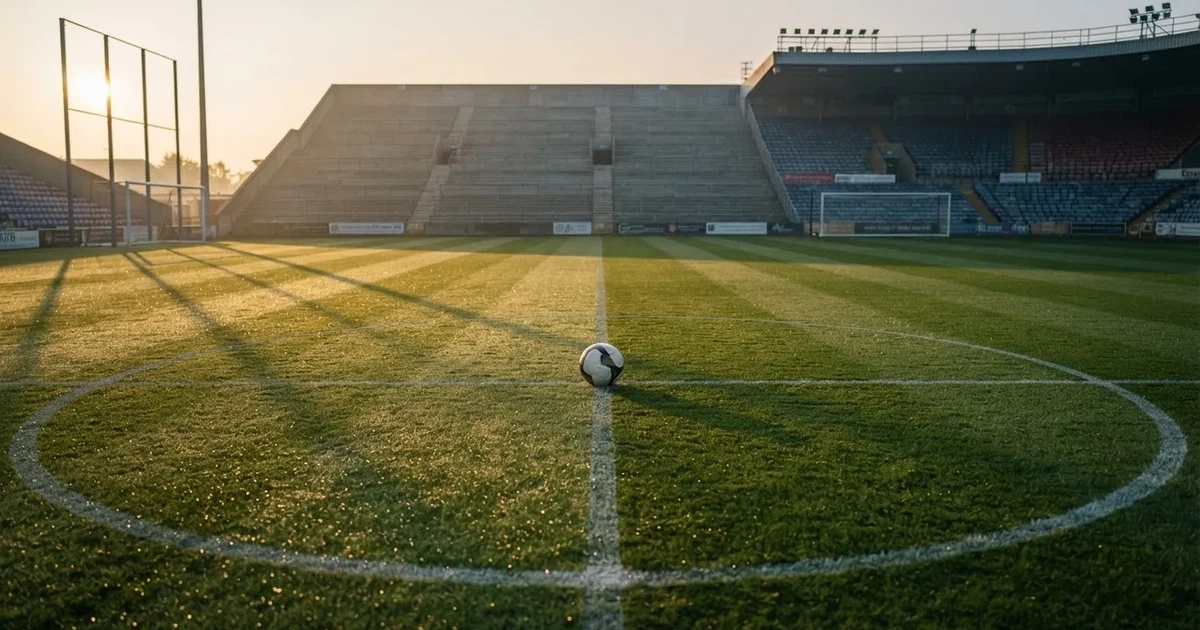 Un balón en el punto central de un campo de césped a la luz de la mañana