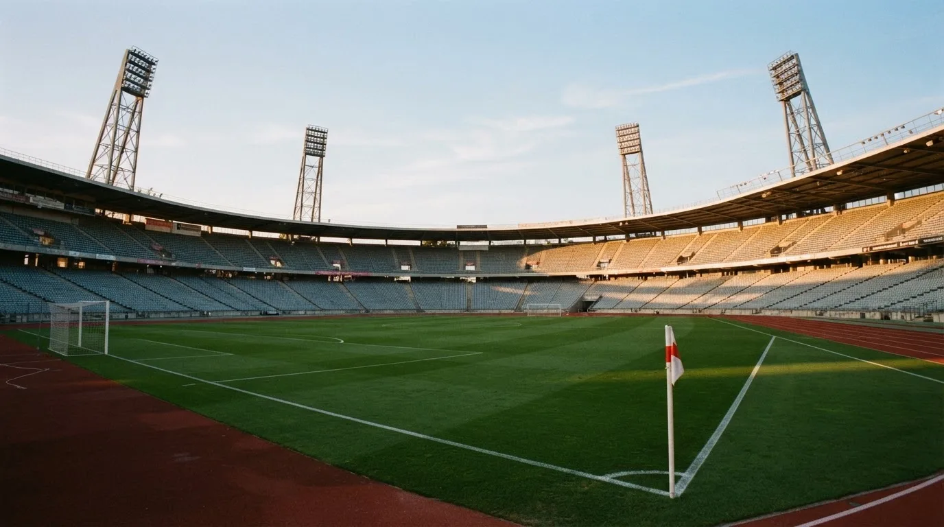 Un estadio de fútbol vacío con torres de iluminación al atardecer