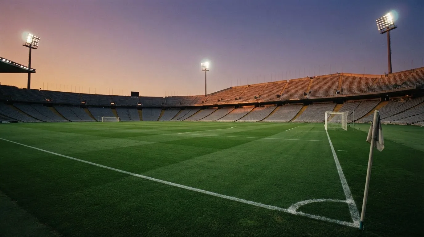Un estadio de fútbol vacío con torres de iluminación al atardecer