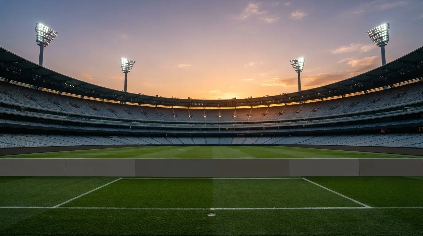 Un estadio de fútbol vacío con torres de iluminación al atardecer