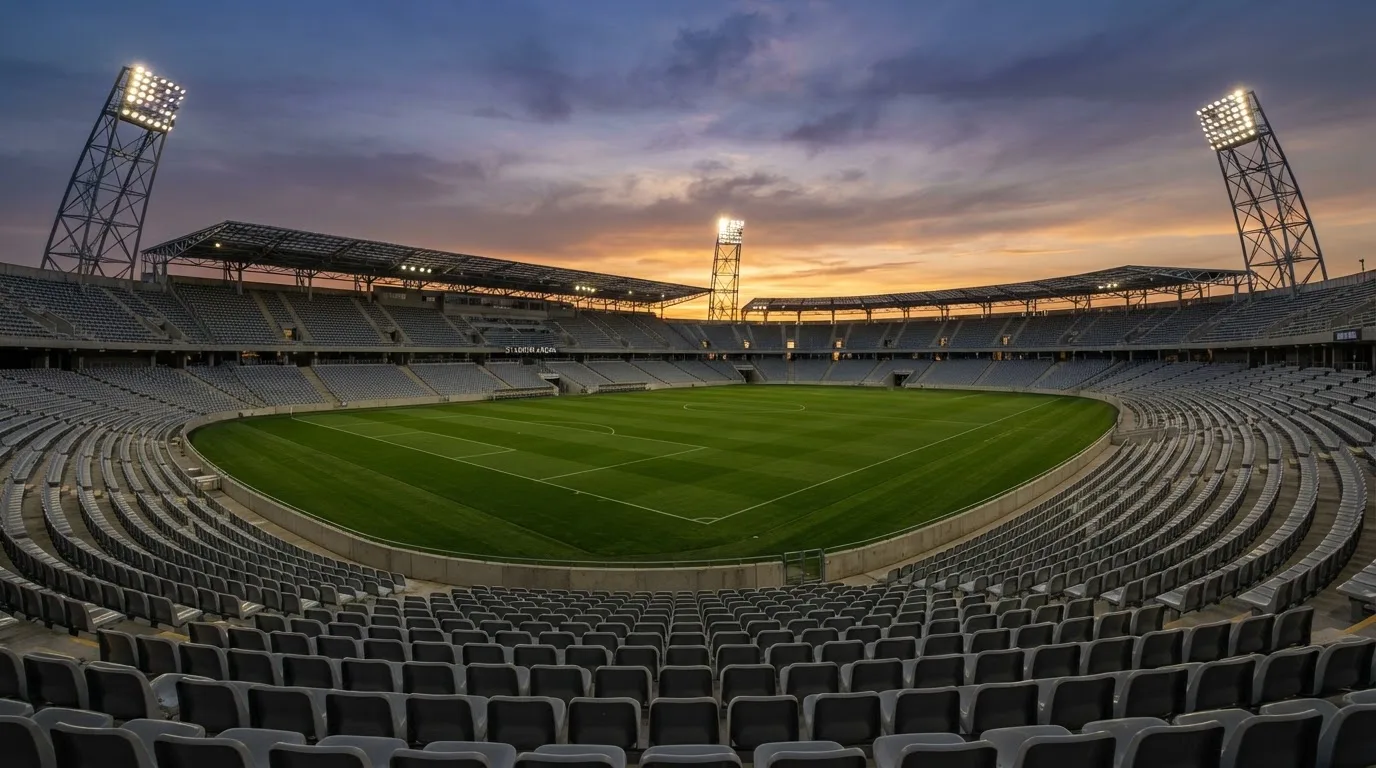 Un estadio de fútbol vacío con torres de iluminación al atardecer