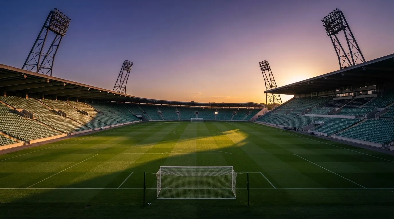 Un estadio de fútbol vacío con torres de iluminación al atardecer
