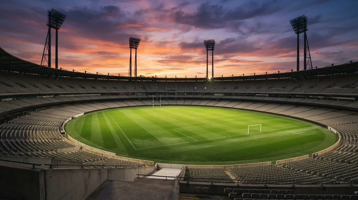 Un estadio de fútbol vacío con torres de iluminación al atardecer