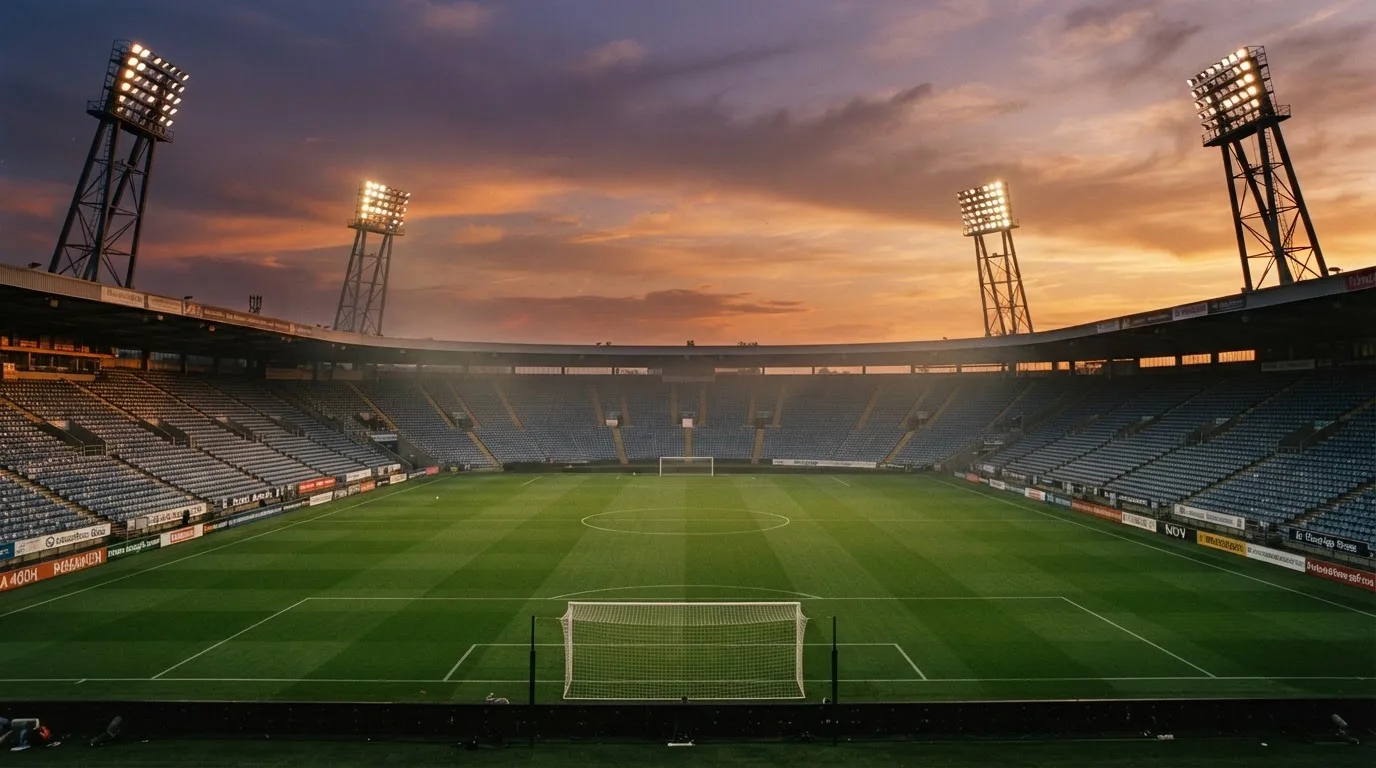 Un estadio de fútbol vacío con torres de iluminación al atardecer