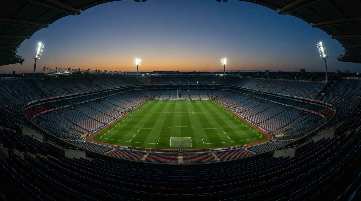 Un estadio de fútbol vacío con torres de iluminación al atardecer
