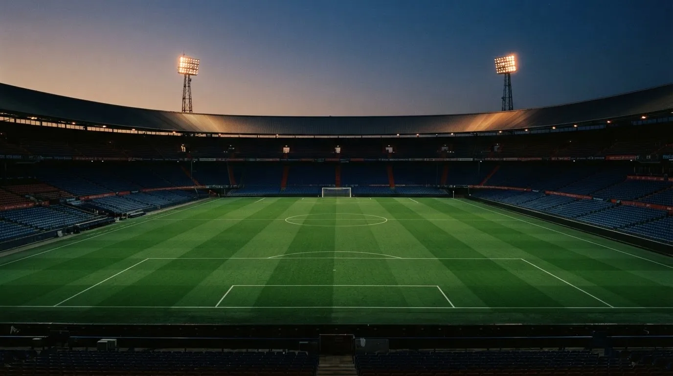 Un estadio de fútbol vacío con torres de iluminación al atardecer