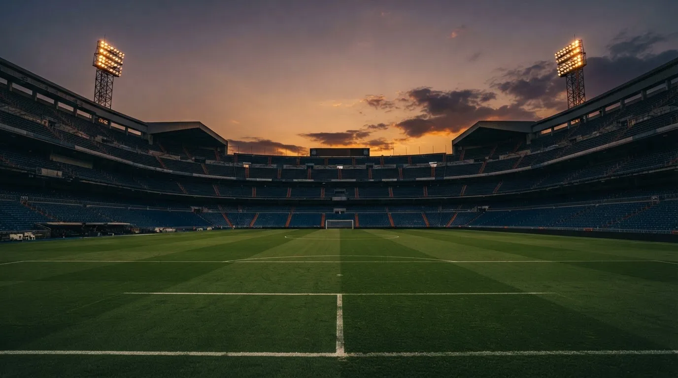 Un estadio de fútbol vacío con torres de iluminación al atardecer