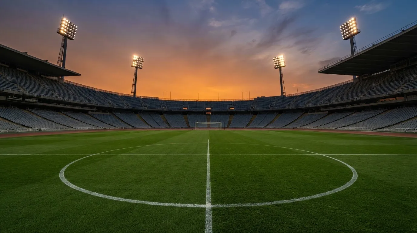 Un estadio de fútbol vacío con torres de iluminación al atardecer