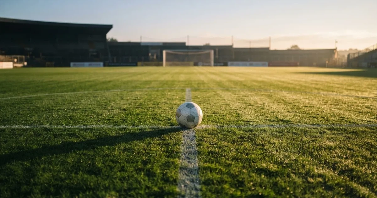 Un balón en el punto central de un campo de césped a la luz de la mañana