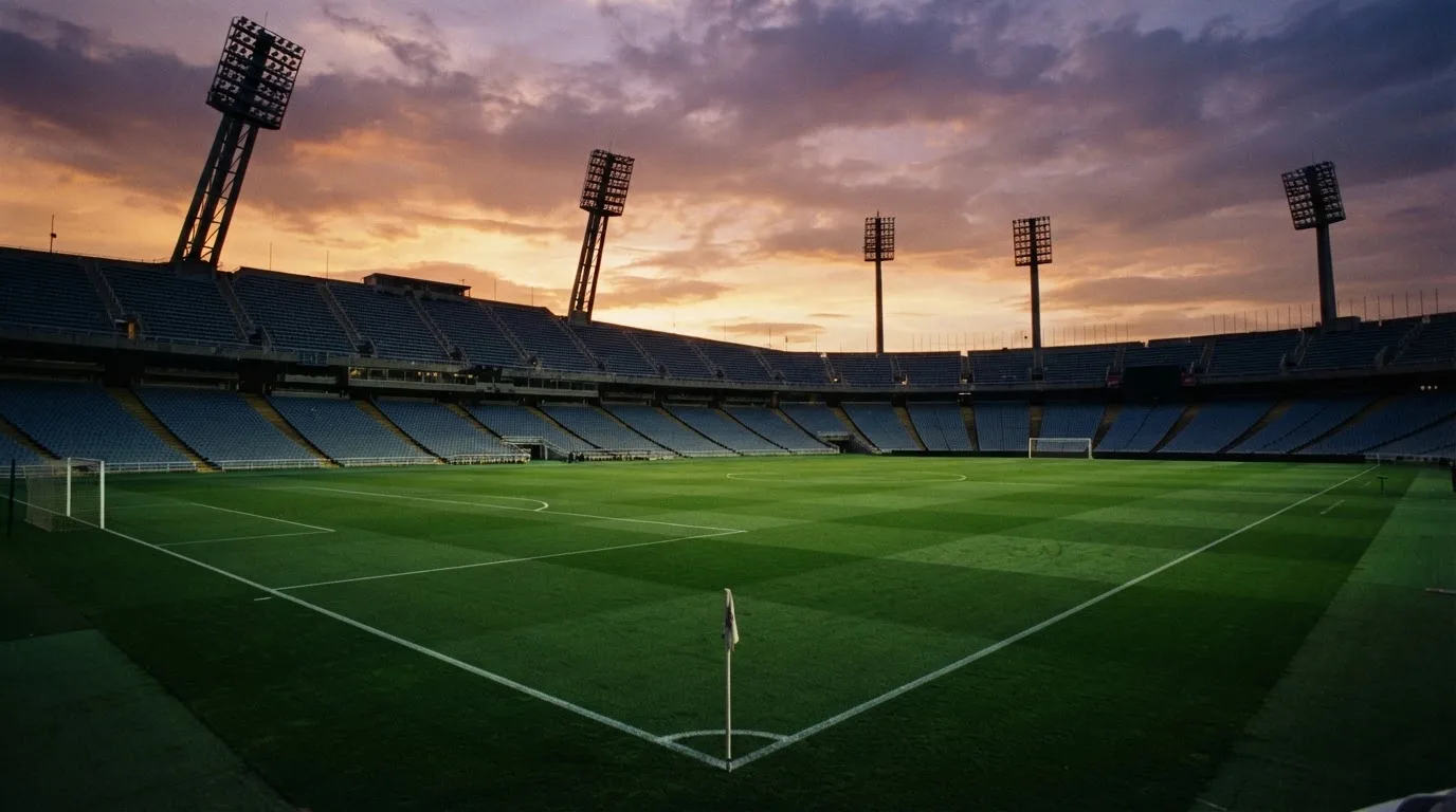 Un estadio de fútbol vacío con torres de iluminación al atardecer