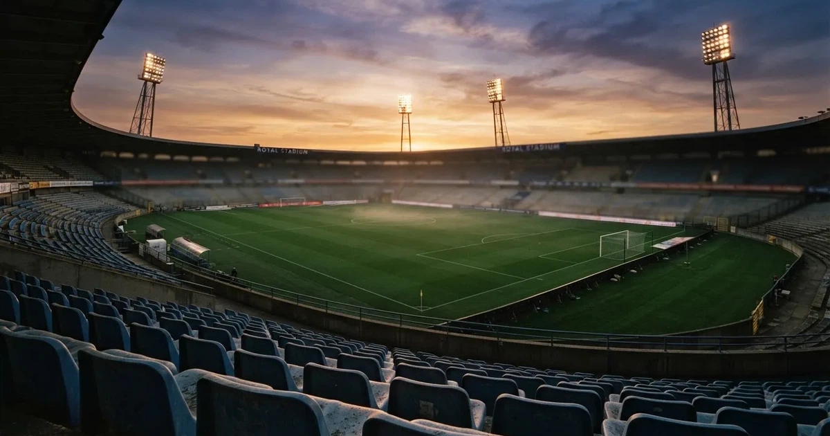 Un estadio de fútbol vacío con torres de iluminación al atardecer